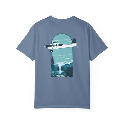 Aviation blue t-shirt featuring a graphic print of a Cessna 180 airplane with a waterfall in the background, positioned above a mountain range.