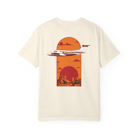 Pilot gear beige tee with a graphic design of a King Air plane flying over a canyon landscape background